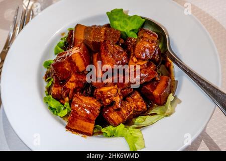 Chinesische tiefgebratene Schweinestückchen mit süßer und saurer Sauce, serviert auf Salatblättern. Hochwertige Fotos Stockfoto