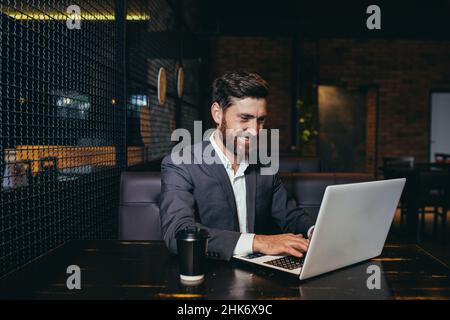 Erfolgreicher Geschäftsmann, der während der Mittagspause im Hotelrestaurant am Laptop arbeitet Stockfoto
