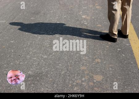 Neu Delhi, Neu Delhi, Indien. 2nd. Februar 2022. Eine Maske, die dem indischen Innenminister Amit Shah ähnelt, liegt auf dem Boden, als ein Polizist während eines Protestes gegen eine angebliche Überwachungsoperation mit der in Israel gebauten Pegasus-Spyware Wache hält. (Bild: © Karma Sonam Bhutia/ZUMA Press Wire) Stockfoto