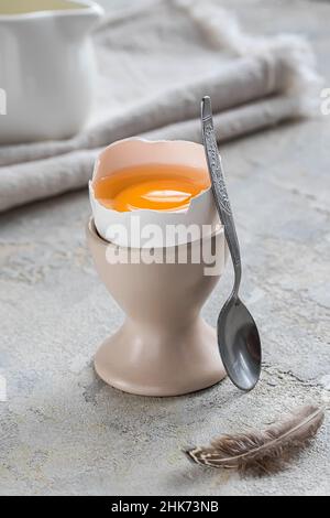 Frisch gebrochenes weich gekochtes Ei auf einem Stand auf weißem Beton rustikalen Hintergrund. Weiche Eier, gesundes Frühstück. Stillleben Frühstück. Stockfoto