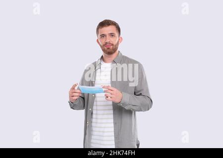 Mann Mit Medizinischer Maske Isoliert. Mann in grünem Hemd zeigt, wie man eine medizinische Maske aufsetzt. Gesundheit, Virus, Medizinisches Konzept. Lernprogramm Stockfoto