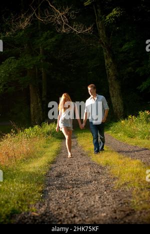 Junges heterosexuelles Paar, das die Auffahrt mit Händen hinuntergeht Stockfoto