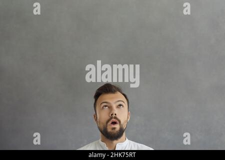 Nahaufnahme des Gesichts eines lustig überraschten und verwirrten kaukasischen Mannes, der über seinen Kopf schaut. Stockfoto