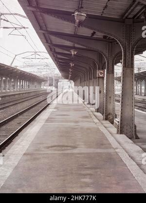 Einsame launische Szene mit einem leeren Bahnhof oder Bahnsteig an einem nebligen Morgen. Stockfoto