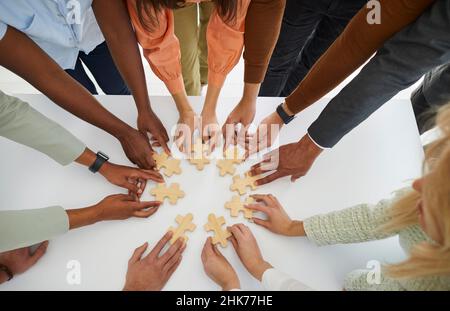 Hände verschiedener Geschäftsleute, die Puzzleteile als Zeichen der Problemlösung und Teamarbeit verbinden. Stockfoto