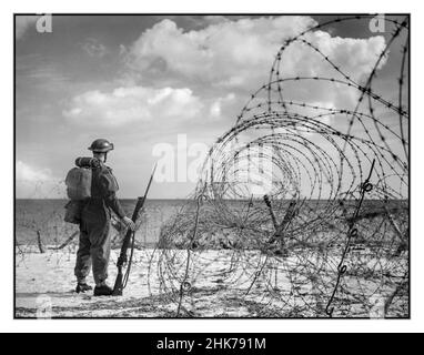 Propagandafoto des Zweiten Weltkriegs von einem britischen Soldaten in kompletter Kriegsausrüstung und Uniform mit Gewehr und festem Bajonett, die an einem Strand in Südengland stehen, Oktober 1940. 2. Weltkrieg die britischen Anti-Invasion-Vorbereitungen des Zweiten Weltkriegs führten zu einer großen Aufteilung der militärischen und zivilen Mobilisierung als Reaktion auf die drohende Invasion (Operation Seelöwe) durch die deutschen Streitkräfte in den Jahren 1940 und 1941. 1,5 Millionen Männer wurden als Teilzeitsoldaten in die Home Guard eingeschrieben. Der rasche Bau von Feldbefestigungen veränderte einen Großteil Großbritanniens, insbesondere Südengland, Stockfoto