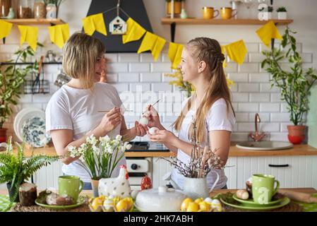 Mutter und Tochter bereiten sich auf die Osterferien vor und malen Eier. Stockfoto