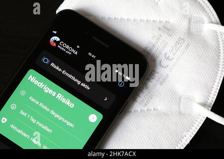 FFP2 Maske und iPhone mit risikoarter Corona-Warnungs-App, Symbol-Smartphone-Apps zum Schutz vor Covid-19, Deutschland Stockfoto