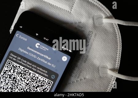 FFP2 Maske und iPhone mit Corona Warnungs-App mit QR-Code für Wiederherstellungszertifikat, symbolisches Bild Smartphone-Apps zum Schutz vor Stockfoto