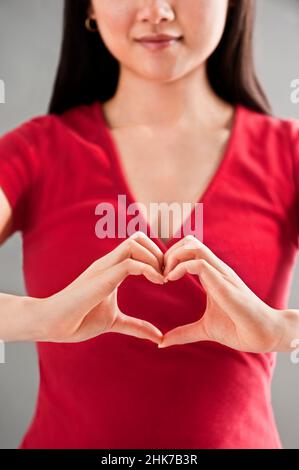 Asiatische Frau macht Herz Zeichen Stockfoto