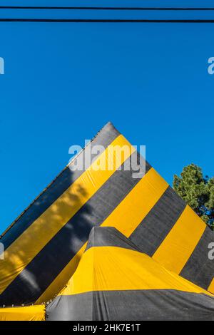 Eine hohe Kirche Mit A-Rahmen und Dach, die zur Begasung mit einer gestreiften Plane mit geometrischem und abstraktem Effekt betagt ist. Stockfoto