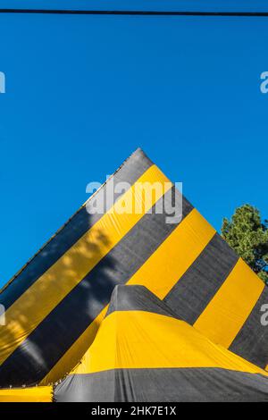 Eine hohe Kirche Mit A-Rahmen und Dach, die zur Begasung mit einer gestreiften Plane mit geometrischem und abstraktem Effekt betagt ist. Stockfoto