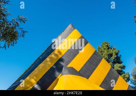 Eine hohe Kirche Mit A-Rahmen und Dach, die zur Begasung mit einer gestreiften Plane mit geometrischem und abstraktem Effekt betagt ist. Stockfoto