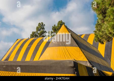 Eine hohe Kirche Mit A-Rahmen und Dach, die zur Begasung mit einer gestreiften Plane mit geometrischem und abstraktem Effekt betagt ist. Stockfoto