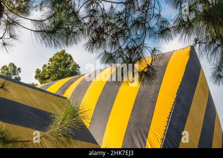 Eine hohe Kirche Mit A-Rahmen und Dach, die zur Begasung mit einer gestreiften Plane mit geometrischem und abstraktem Effekt betagt ist. Stockfoto