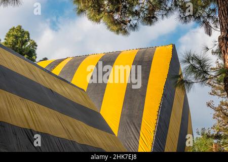 Eine hohe Kirche Mit A-Rahmen und Dach, die zur Begasung mit einer gestreiften Plane mit geometrischem und abstraktem Effekt betagt ist. Stockfoto