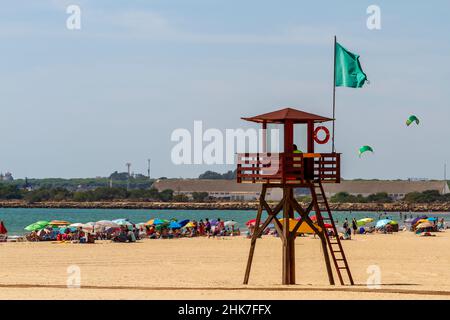 Rettungsschwimmer, die vom Strandwachturm aus beobachten, um die Badegäste beim Sonnenbaden am Ufer und beim Baden im Meer zu schützen. Alle Menschen in diesem Bild Stockfoto