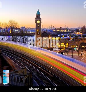 Stimmungsvolle Lichtspuren bewegter Hochbahn und Uhrenturm bei Sonnenaufgang, Landungsbrücken, St. Pauli, Hamburg, Deutschland Stockfoto