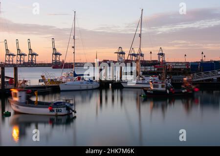 Die Sonne beginnt zu untergehen, mit Blick auf den Hafen von Felixstowe und Kräne vom Hafen von Harwich und dem Ha'Penny Pier. Harwich & Dovercourt, Essex, Großbritannien Stockfoto