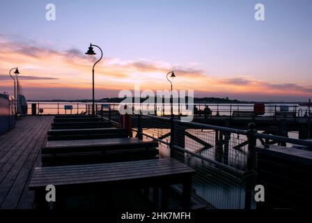 Sonnenuntergang über dem historischen Ha'Penny Pier in Harwich, North Essex, Großbritannien. Der Abendhimmel spiegelt sich auf dem glatten Wasser des Flusses Stour wider. Stockfoto