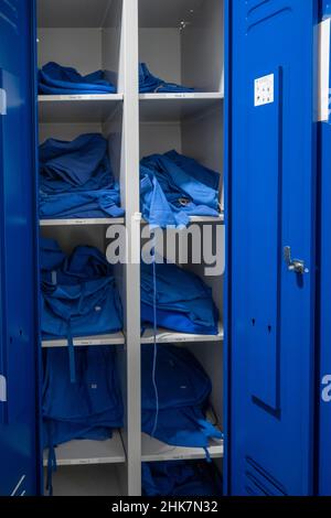 Im Schrank befindet sich blaue Krankenhauskleidung in verschiedenen Größen Stockfoto