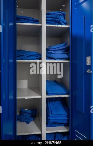 Im Schrank befindet sich blaue Krankenhauskleidung in verschiedenen Größen Stockfoto