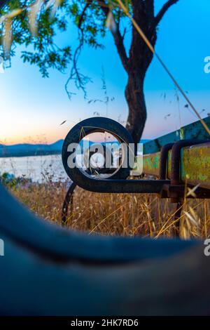 Vertikale Aufnahme einer alten rostigen Bank am See Stockfoto