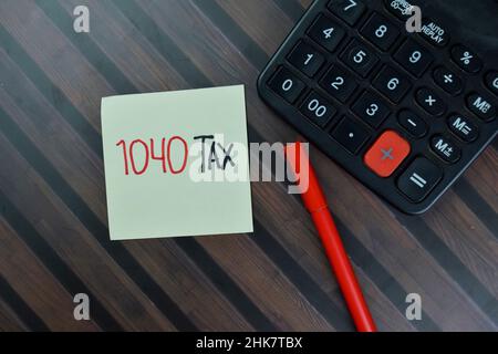 1040 Steuer Schreiben Sie auf Haftnotizen isoliert auf Holztisch. Stockfoto