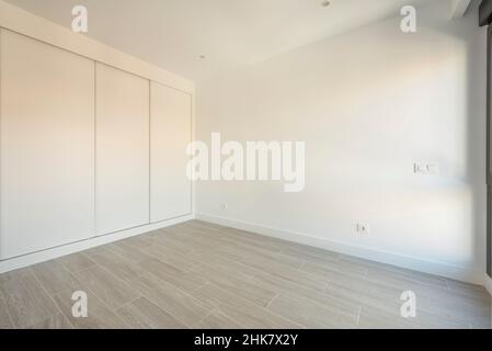 Leeres Schlafzimmer mit Einbauschrank mit Wand-zu-Wand-Schiebetüren und Steinzeugböden Stockfoto