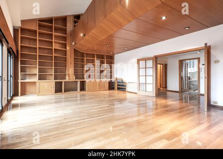 Loft mit großer Bücherregal aus hellem Holz an der Wand und einem oberen Teil mit Holztäfelung und Eichenparkettböden Stockfoto