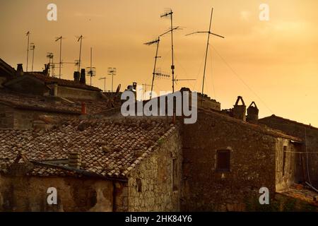Blick auf die Stadt Pitigliano bei Sonnenuntergang, die sich auf einem vulkanischen Tuffsteinkamm befindet, der als das kleine Jerusalem bekannt ist und von üppigen Tälern umgeben ist. Etruskische Erbe, Gros Stockfoto