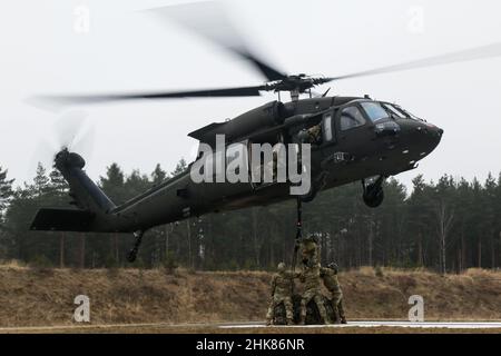 Luftangriffslehrer und Studenten führen Schlingentraglasoperationen mit UH-60 Blackhawk-Hubschraubern durch, die dem Bataillon 1st, dem Aviation Regiment 214th und dem Combat AVN 12th zugeordnet sind. Brigade, während des Luftansturzkurses der US-Armee im Trainingsgebiet Grafenwoehr, Deutschland, 27. Januar 2022. Das Combined Arms Training Center des Army Training Command 7th sponserte den zehntägigen Flugkurs, der von Ausbildern des Warrior Training Center der Army National Guard in Fort Benning, Georgia, angeboten wurde. Der Kurs schult Soldaten bei Luftangriffen, Schleuderbelastungen und Abseilen, um die Nutzung von h zu maximieren Stockfoto