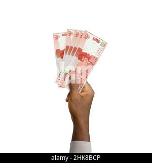 Schwarze Hand mit 3D gerenderten 100000 indonesischen Rupiah-Noten isoliert auf weißem Hintergrund Stockfoto