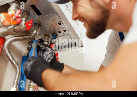 Nahaufnahme des Klempners mit Schraubendreher während der Installation neuer Stahl-Warmwasser-Zentralheizung in der Wohnung Stockfoto