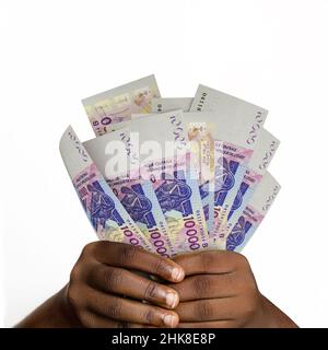 Schwarze Hände mit 3D gerendert 10000 westafrikanischen Cfa-Franc-Noten. Nahaufnahme der Hände mit Cfa-Franc-Währungsnoten Stockfoto