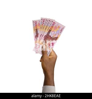 Schwarze Hand mit 3D gerenderten 1000 westafrikanischen CFA-Noten isoliert auf weißem Hintergrund Stockfoto