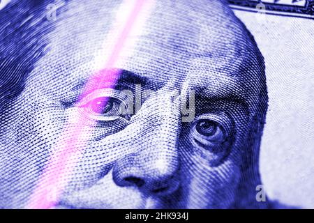 Überprüfung von Dollarnoten im UV-Licht. Fälschungsgeld-Konzept. Benjamin Franklin blickt aus einem Fragment neuer 100 Dollar Stockfoto