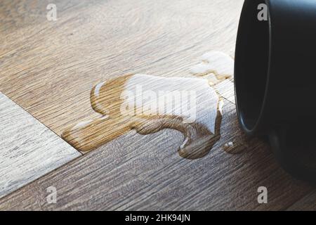 Laminat und Wasser. Wasserdichtes Laminat. Holzböden sind unempfindlich gegen Feuchtigkeit. Bodenbeläge schützen vor Wasser. Eine Pfütze auf dem Boden. Stockfoto