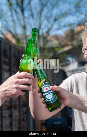 22.04.2019. London, Vereinigtes Königreich. Eine Gruppe von Freunden, die im Garten ein Heineken-Lagerbier in Flaschen trinken Stockfoto