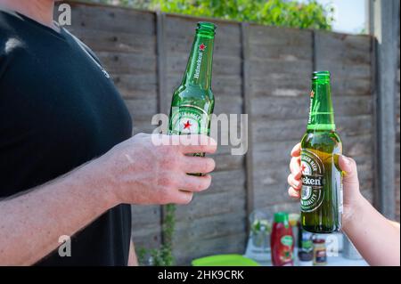 22.04.2019. London, Vereinigtes Königreich. Eine Gruppe von Freunden, die im Garten ein Heineken-Lagerbier in Flaschen trinken Stockfoto