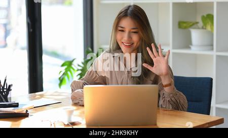 Attraktive und selbstbewusste asiatische Arbeitnehmerin oder Geschäftsfrau, die ein Online-Meeting mit ihrem Team führt Stockfoto