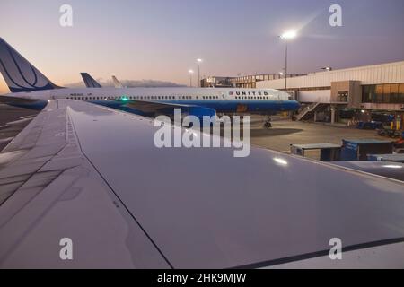 Ein Blick vom Fenstersitz, während das Flugzeug bei Sonnenaufgang das Tor verlässt Stockfoto