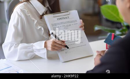 Bild in Nahaufnahme übergibt Eine Immobilienmaklerin einen Mietvertrag an einen neuen Mieter, der seine Unterschrift zur Zustimmung zu den Bedingungen unterzeichnet hat. Stockfoto