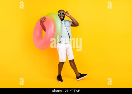 In voller Länge Körpergröße Ansicht der attraktiven verrückten fröhlichen Kerl trägt Gummikreis isoliert über helle gelbe Farbe Hintergrund Stockfoto