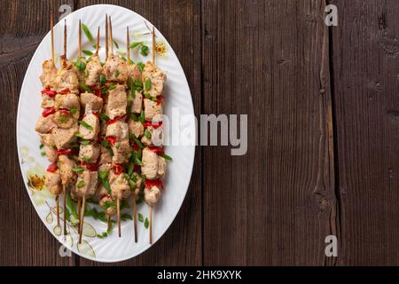 Fleischkebabs auf einer großen Platte mit Saucen und Kräutern, Holzhintergrund mit Kopierraum Stockfoto