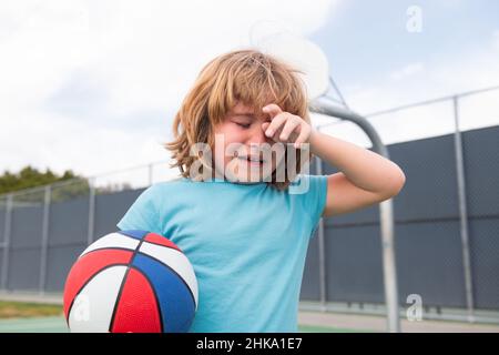 Junge weint vor Groll und Trauer. Kleiner Junge allein, einsam mit Ball. Einsamkeit Kinder. Trauriges Kind Junge Porträt Stockfoto