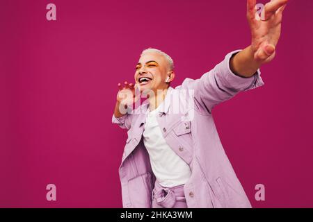 Hipster genießt seine Lieblingsmusik. Nicht konformer queerer Mann, der fröhlich tanzt, während er Musik über kabellose Kopfhörer hört. Lächelnder junger Mann st Stockfoto