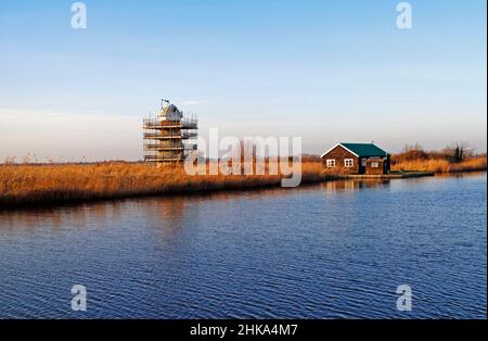 Ein Blick über den Fluss Thurne zu Horning Marshes und Mühle in Restaurierung auf den Norfolk Broads aus Thurne, Norfolk, England, Großbritannien. Stockfoto