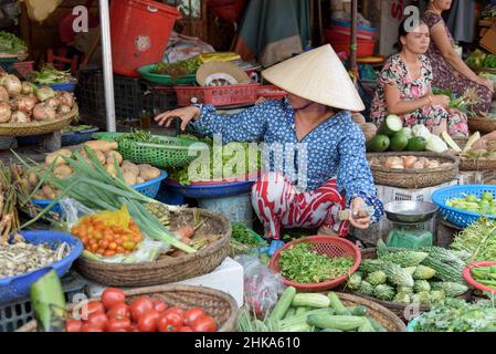 Eine Vietnamesin, die einen traditionellen konischen Hut trägt, verkauft Gemüse auf einem lokalen Lebensmittelmarkt in Hue, Provinz Thua Thien Hue, Zentralvietnam Stockfoto