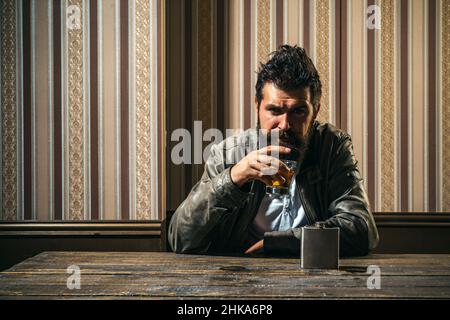 Degustation mit teurem Whiskey. Bärtiger Mann mit einem Glas Whiskey. Männliches Model trinkender Brandy oder Cognac. Teure Getränke. Stockfoto